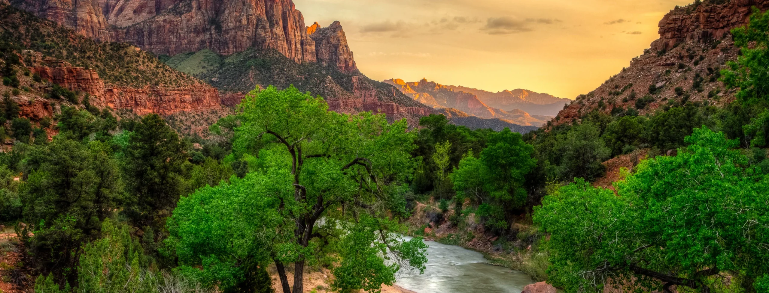 landscape picture of a mountain range with a body of water and forest