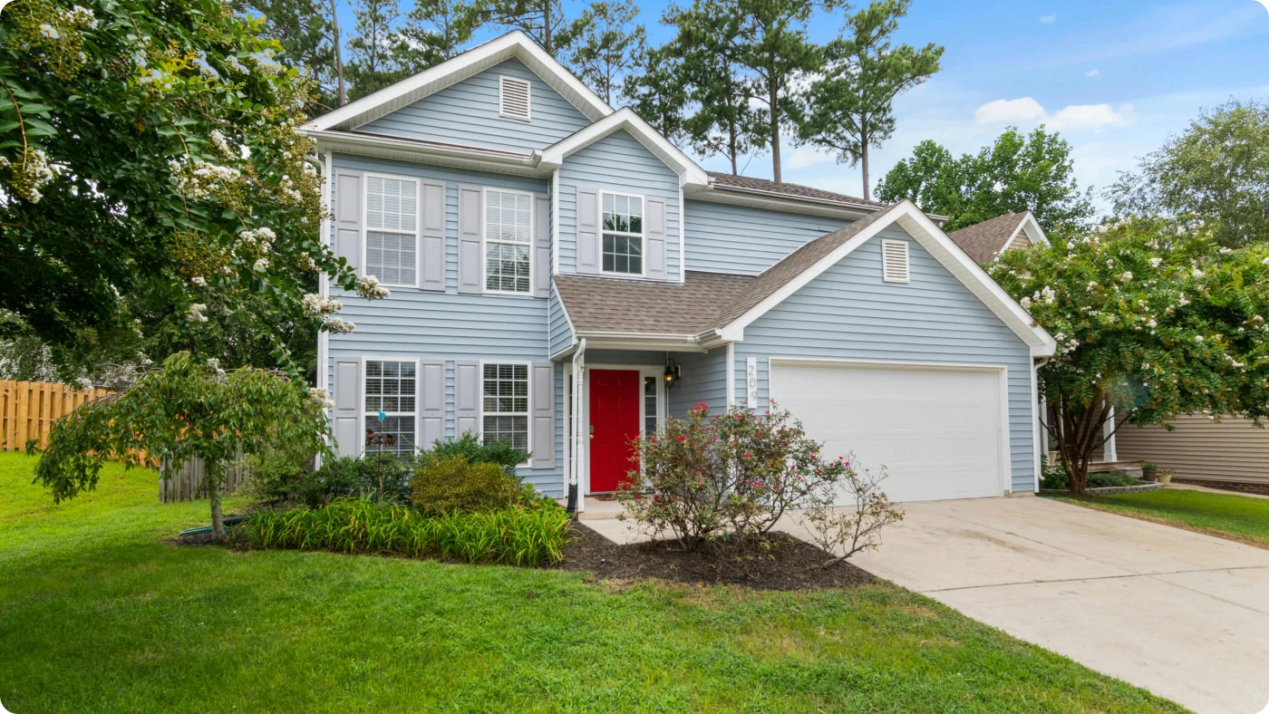 home front showing a light blue house and it's lawn