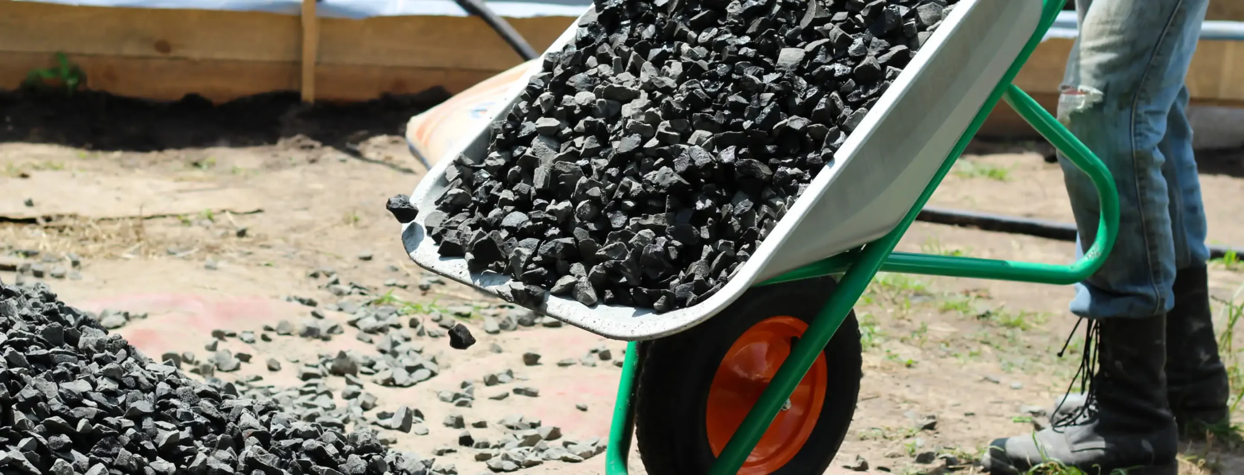person transporting rocks using a wheelbarrow